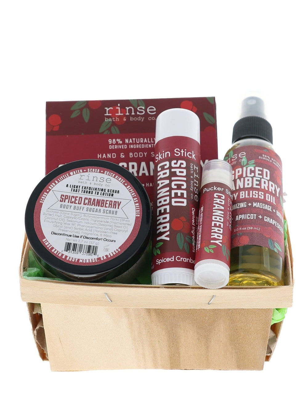 Spiced Cranberry travel set nestled in a wood berry till — green crinkle fill and burgundy labels on bright white