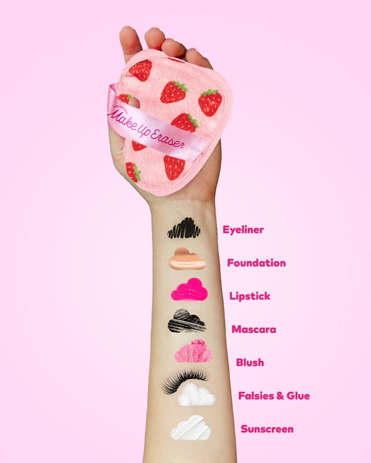 Hand holding strawberry-print MakeUp Eraser cloth above makeup and sunscreen swatches — how the cloth erases everyday makeup