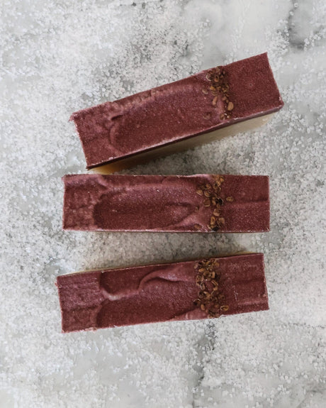 Sugared Fig soap tops on coarse white crystals — deep plum swoops with dried botanical seeds in studio light