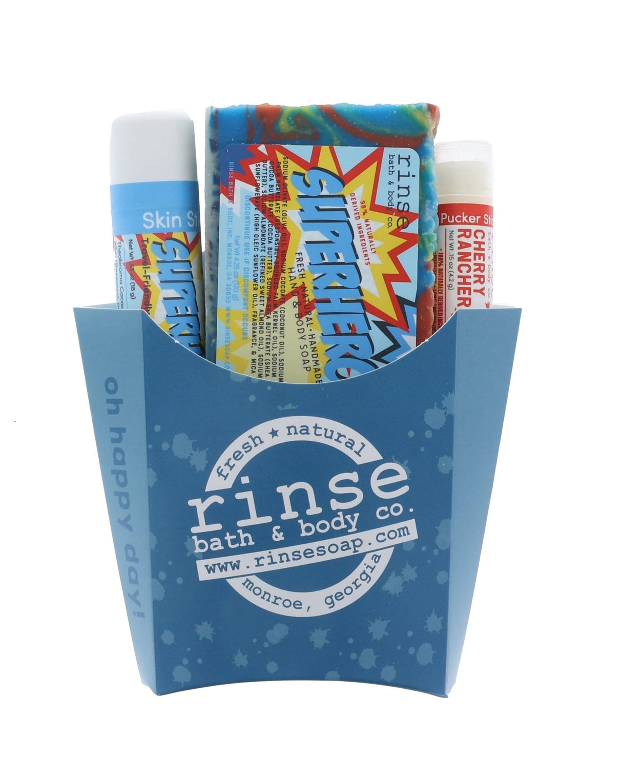 The Superhero kids gift set in its blue carton — rainbow-swirl bar soap, Superhero solid lotion skin stick and a Cherry Rancher lip balm. Rinse Bath & Body Co.