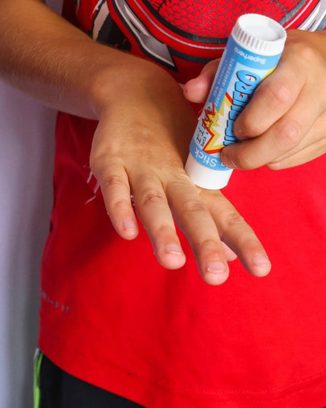 Hands gliding Superhero Skin Stick over dry knuckles — solid lotion in daily use