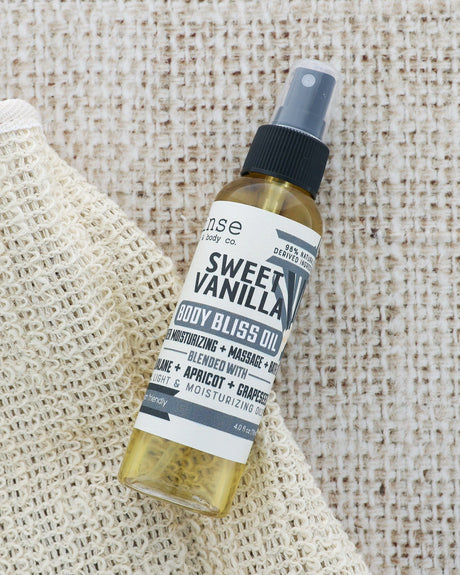 Sweet Vanilla Body Bliss oil close up, showing its light golden texture — sinks in without a greasy finish. Rinse Bath & Body Co.