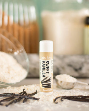Sweet Vanilla solid lotion stick uncapped, showing the poured lotion bar inside its twist-up tube — no bottle, no mess, goes in a pocket. Rinse Bath & Body Co.
