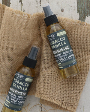 Tobacco Vanilla Body Bliss oil in its bottle, label facing out — grapeseed and apricot kernel, no greasy finish. Rinse Bath & Body Co.