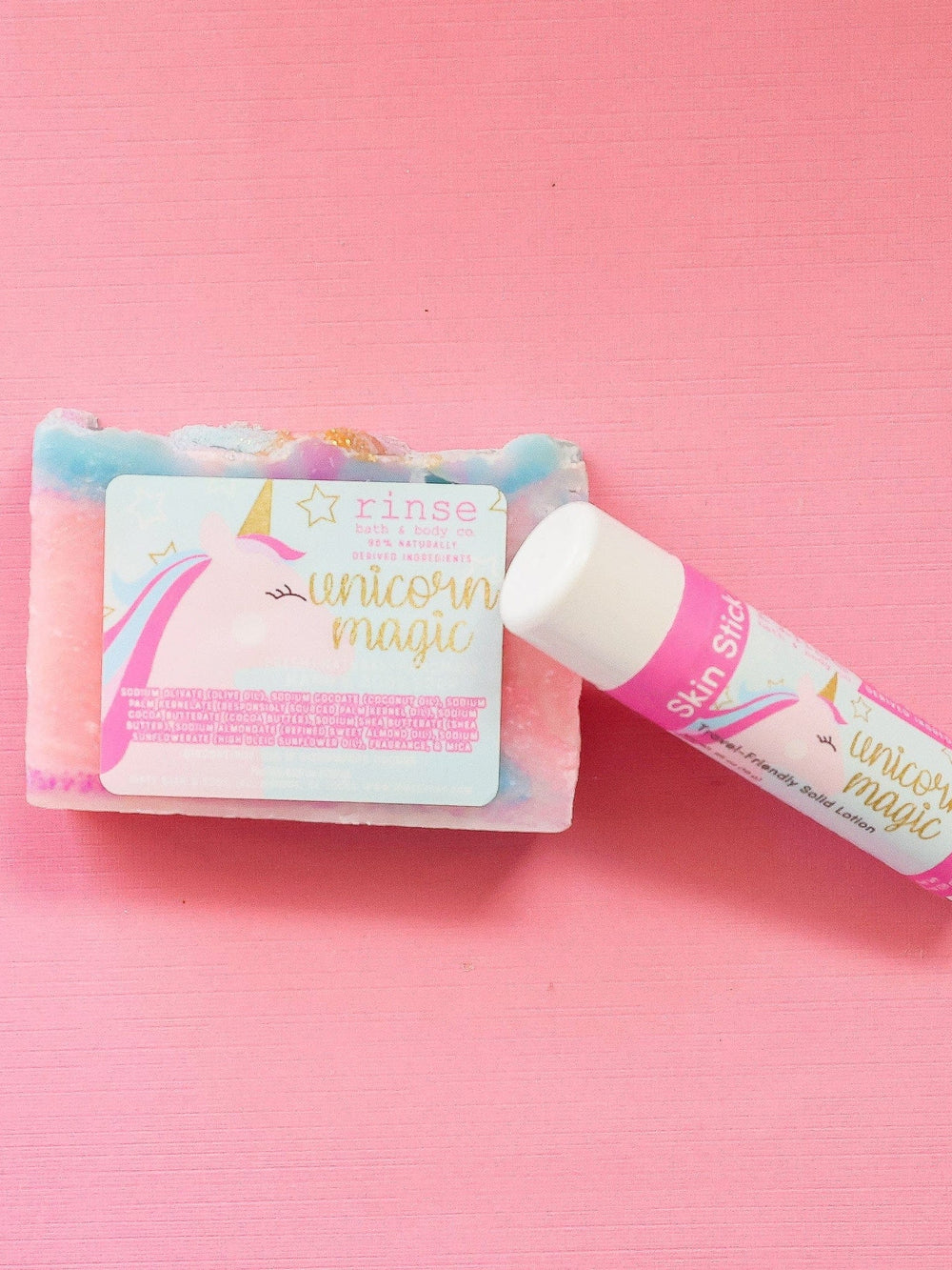 Open Unicorn Magic Skin Stick leaning on pink-blue marble soap — vibrant pink surface in bright even light