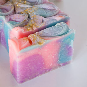 Unicorn Magic soap shows pink-blue marble swirls and gold glitter ridges on bright white