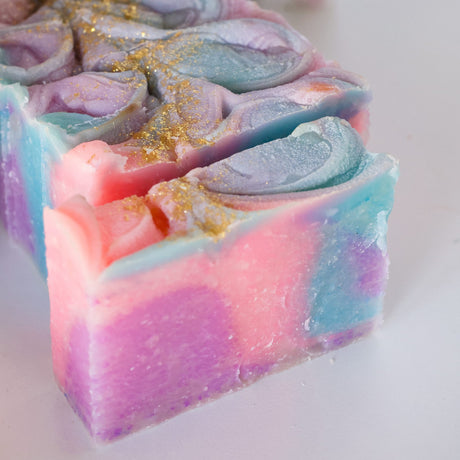 Unicorn Magic soap shows pink-blue marble swirls and gold glitter ridges on bright white