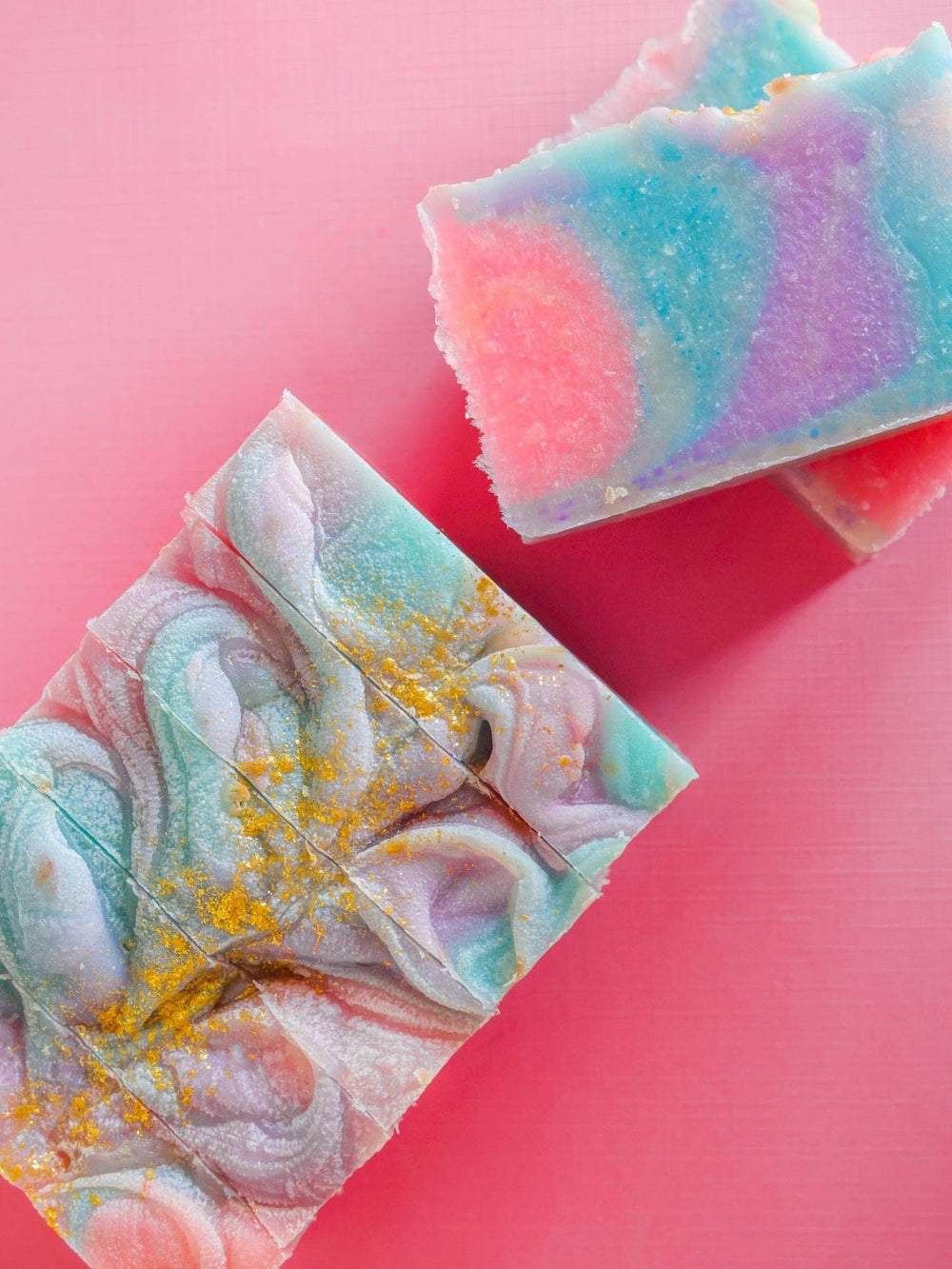 Unicorn Magic soap block and slice on hot pink — pastel swirls dusted with gold glitter