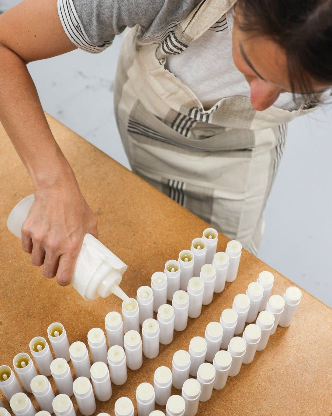 Vanilla Honeycomb solid lotion stick uncapped, showing the poured lotion bar inside its twist-up tube — no bottle, no mess. Rinse Bath & Body Co.
