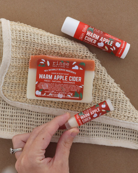 Hand holding Warm Apple Cider soap with rich lather worked up — cocoa-butter bar in use