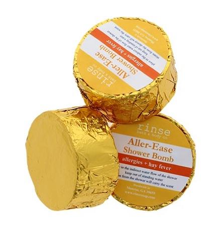Three gold-foil Aller-Ease Shower Bombs cluster — crinkled metallic wrap catching bright studio light