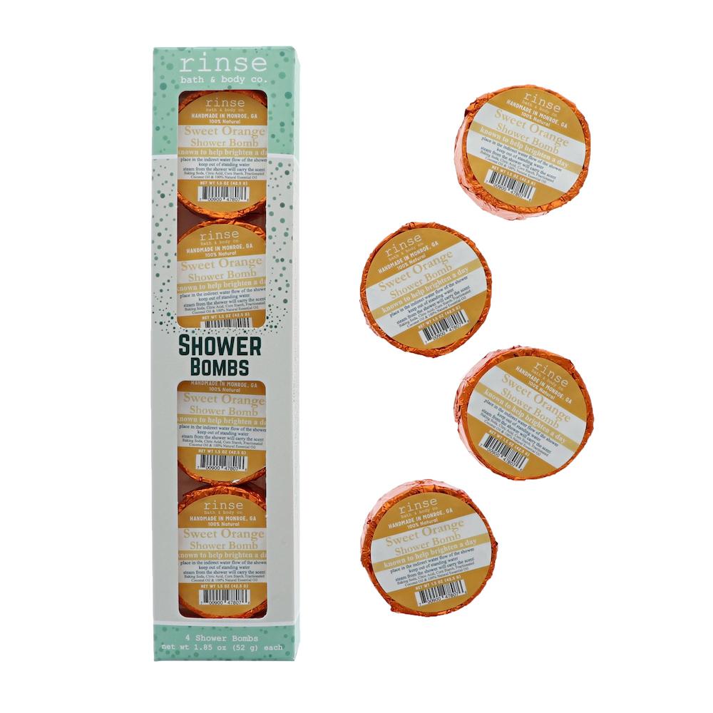 Sweet Orange 4-pack carton stands beside four orange-foil pucks — scattered on clean bright white