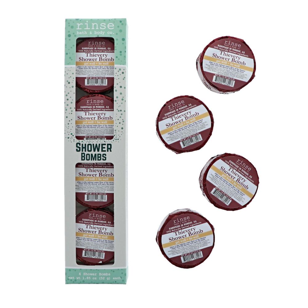 Mint polka-dot Shower Bomb carton stands beside four maroon-foil Thievery pucks — clean bright white studio