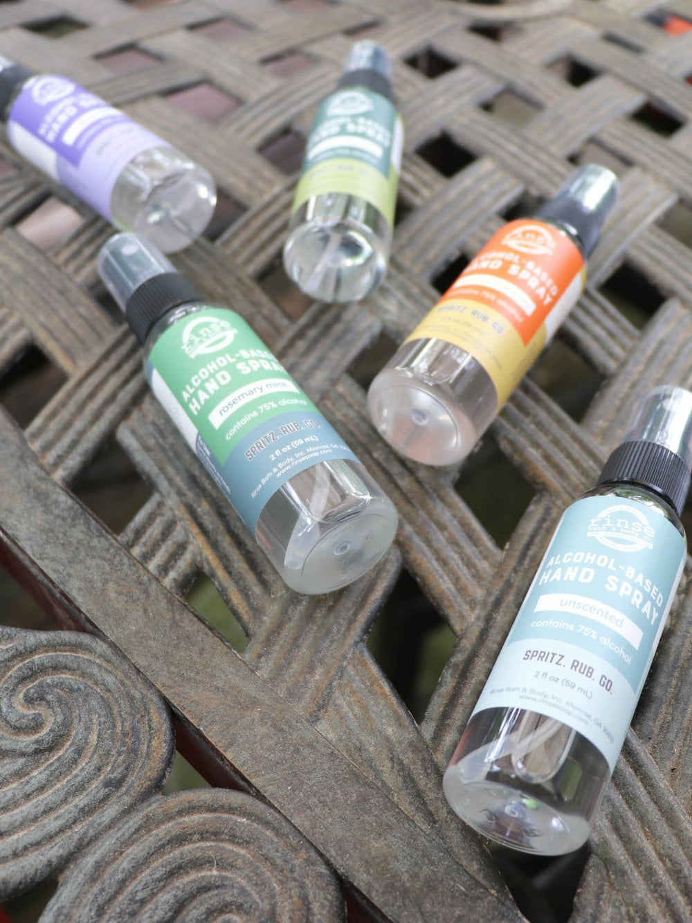 Five colorful hand sprays scatter across ornate metal scrollwork — dark patio table outdoors