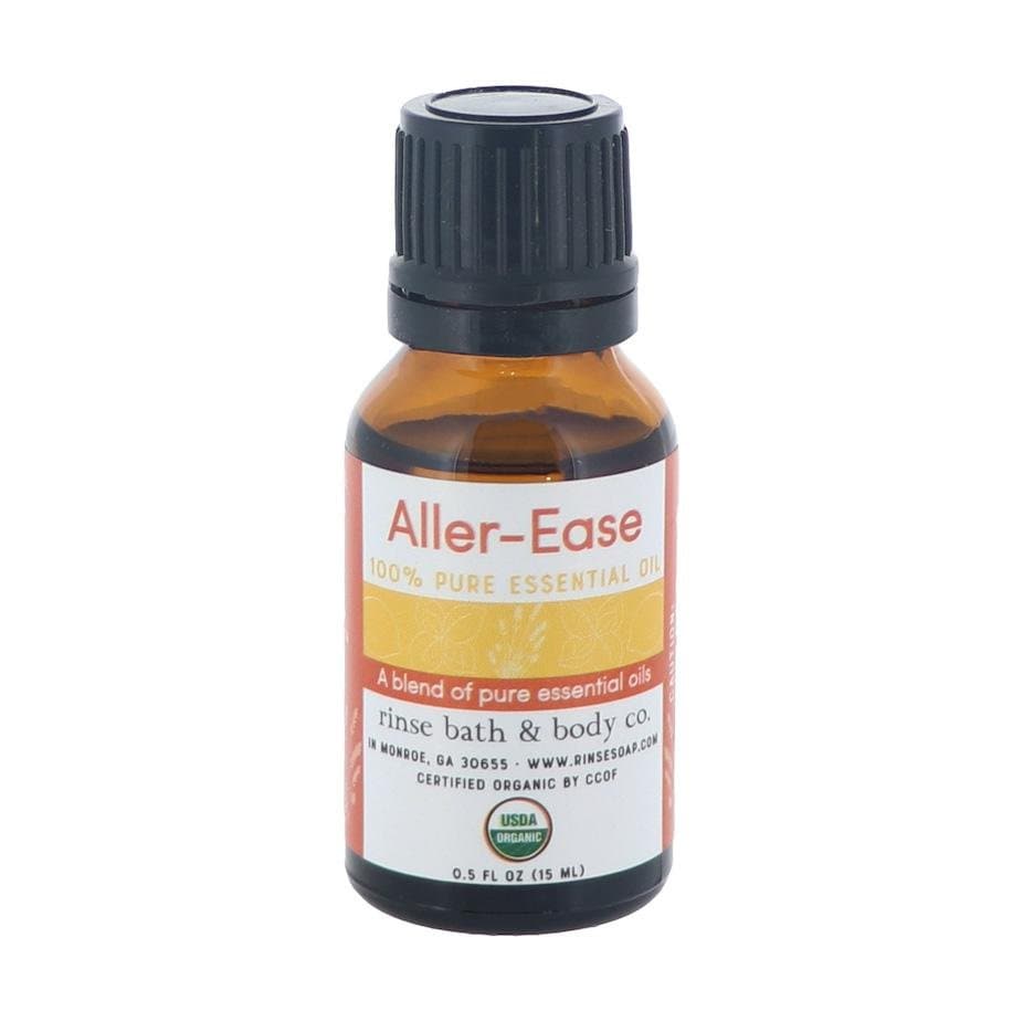 Aller-Ease essential oil bottle standing on bright white — amber glass with orange-red blend label and black ribbed cap in studio light
