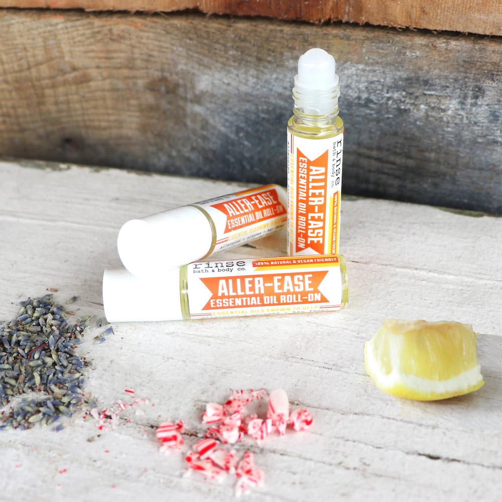 Aller-Ease bottles with lavender buds peppermint bits and a lemon wedge — weathered white wood in bright light