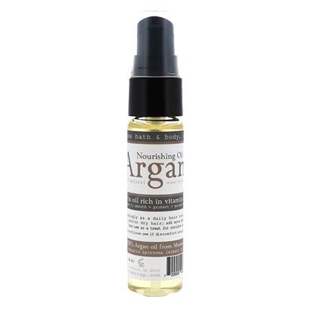 Clear Argan Nourishing Oil bottle standing on bright white — golden oil and black pump in clean studio light