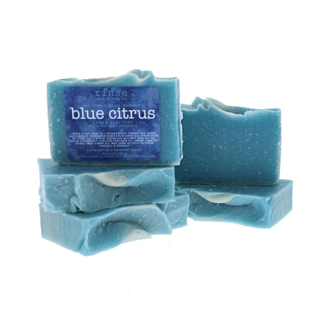 Four Blue Citrus soap bars stack and lean — dusty teal flecks on clean bright white