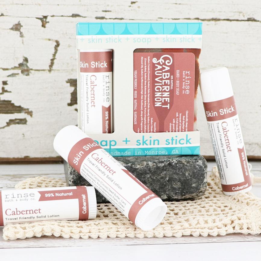 Cabernet soap Skin Stick gift box on dark stone — extra sticks on crocheted cloth against distressed white wood