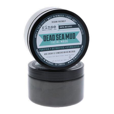 Stacked Dead Sea Mud Facial Mask jars on bright white — charcoal mud through translucent walls and teal purifying label on the lid
