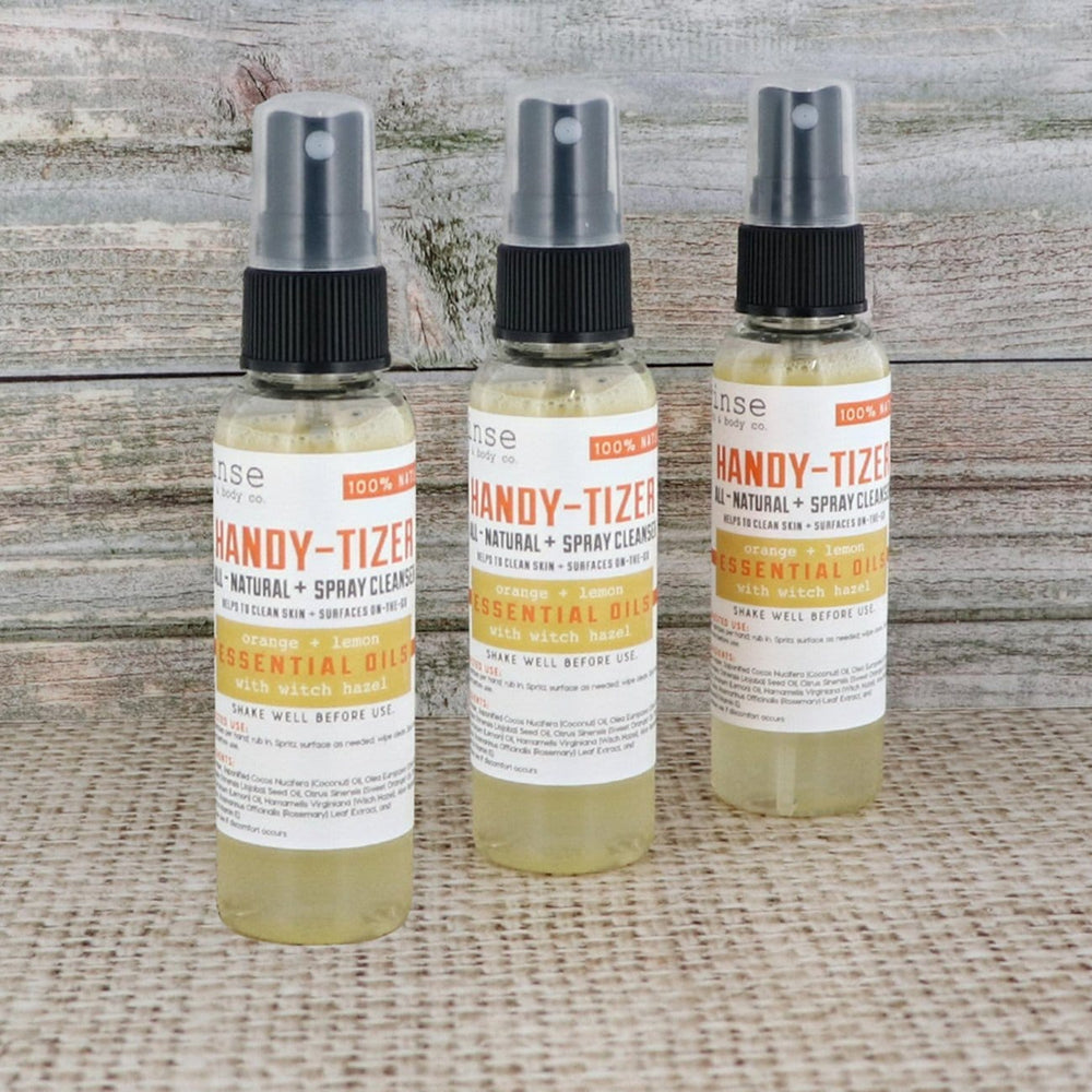Three Orange Lemon Handy-Tizer bottles lined on burlap against weathered wood — bright citrus mist for clean hands anywhere
