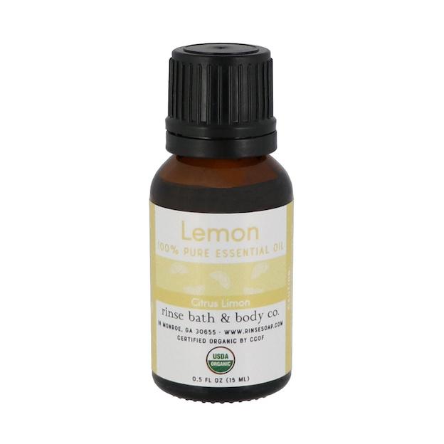 Lemon essential oil bottle standing on bright white — amber dropper with USDA Organic seal in studio light