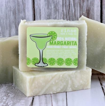 Stacked Margarita soaps sit on weathered white wood — mint labels catching soft daylight