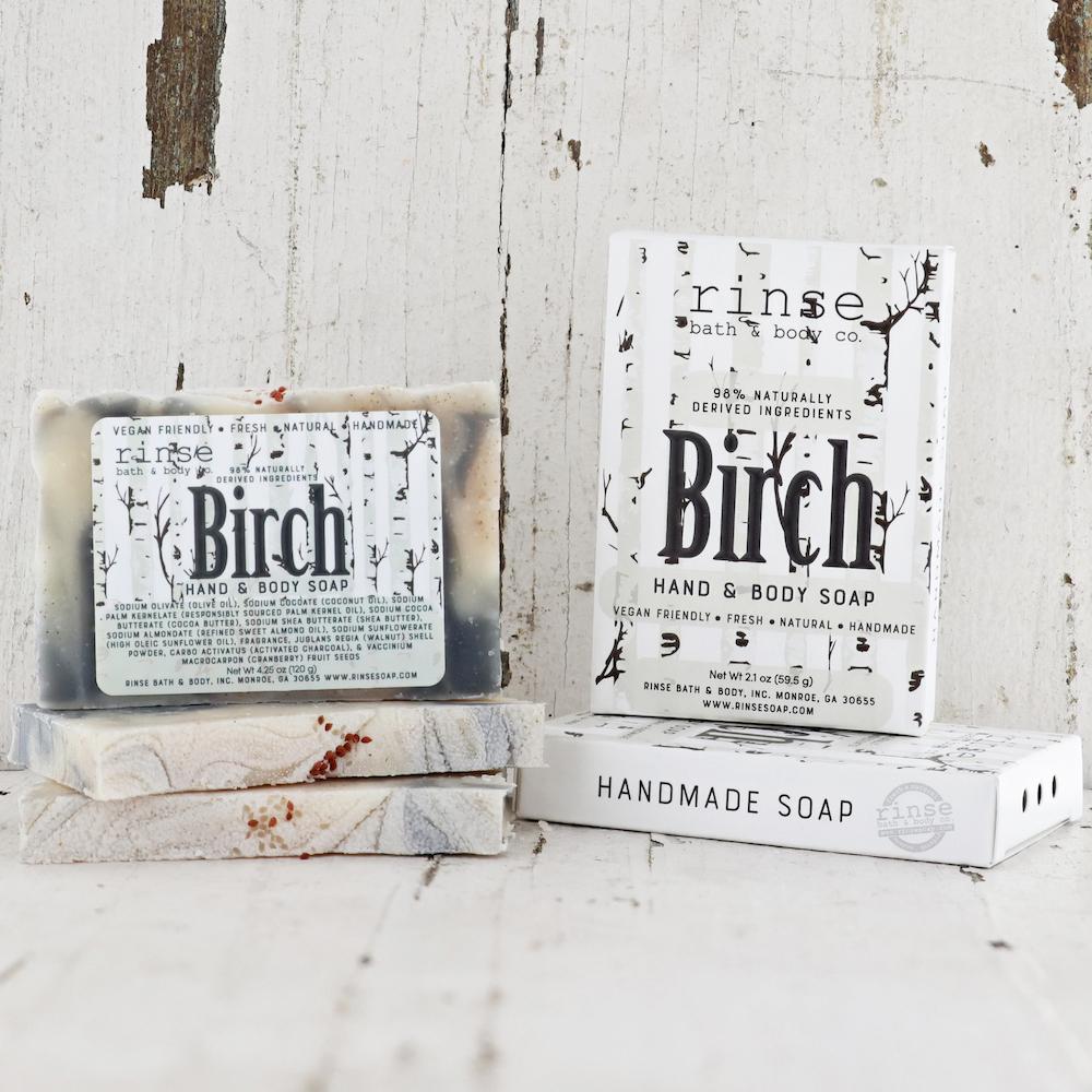 Birch soap stack before weathered whitewashed wood — gray marble bar and upright carton in rustic light