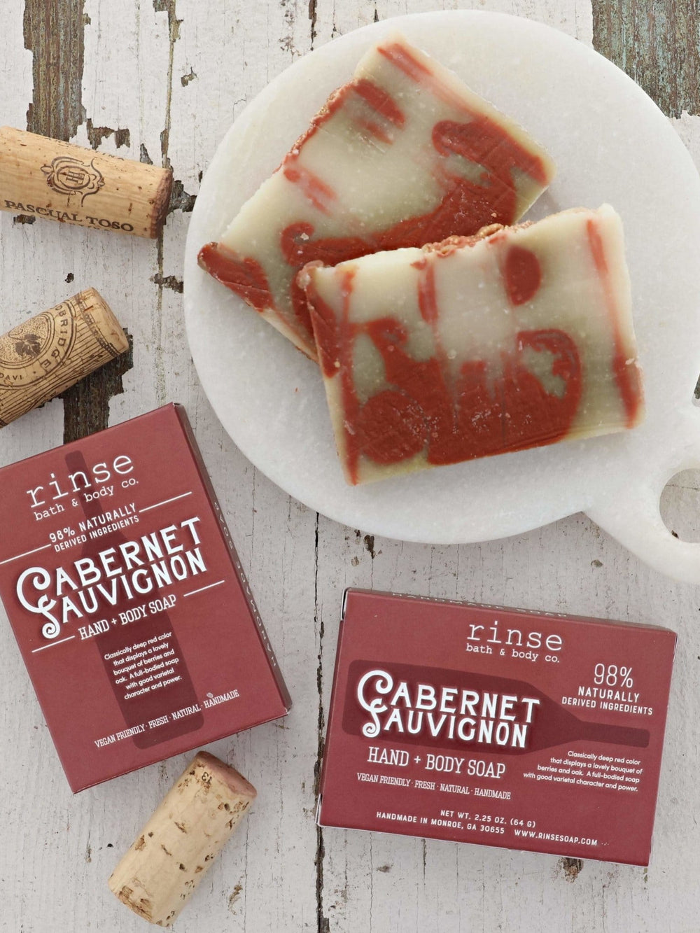 Marbled Cabernet soap bars on a white marble board with corks — distressed white wood flat lay
