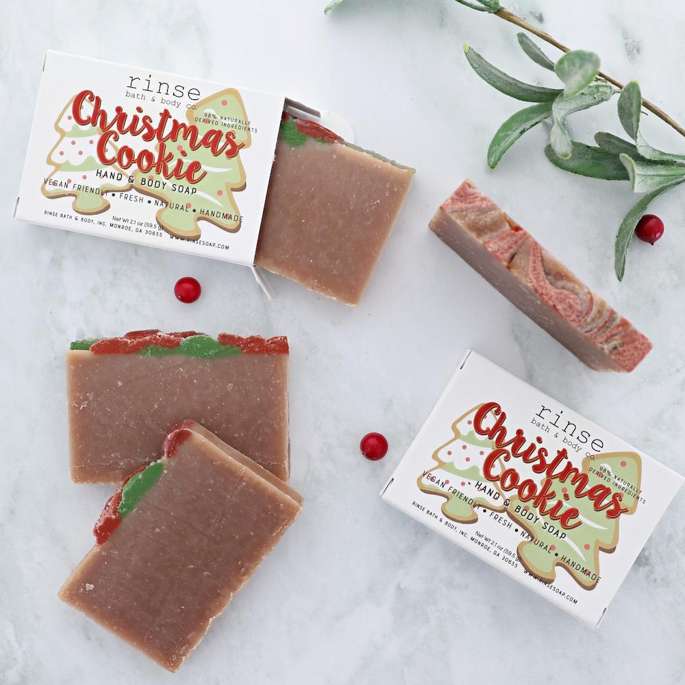 Cookie soaps scatter on white marble — boxes, berry sprig, and brown bars with festive tops