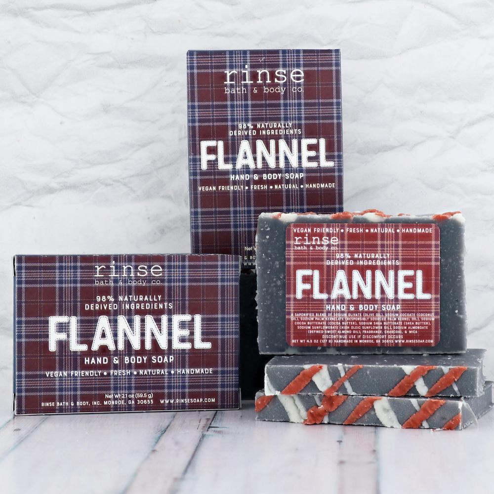 Flannel plaid boxes and charcoal bars with white-and-orange stripes on crinkled white — cozy tartan packaging in bright light