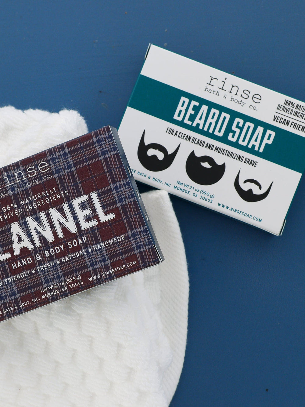 Flannel plaid and Beard Soap boxes angled on waffle cloth and deep blue — travel minis in soft daylight