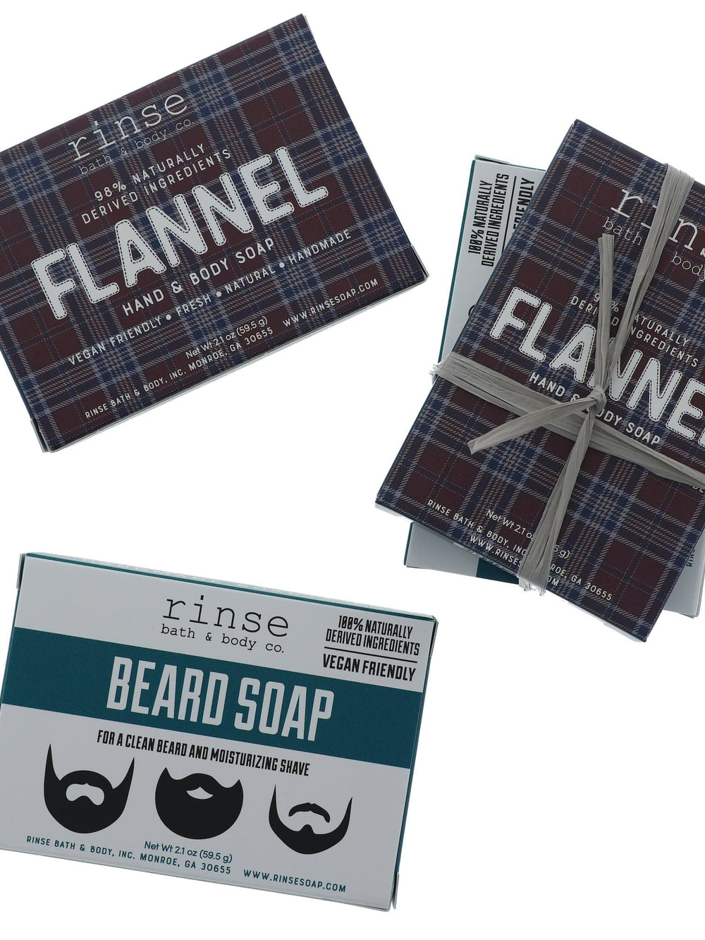 Flannel and Beard Soap mini boxes on bright white — plaid and teal singles beside a gray-raffia gift stack