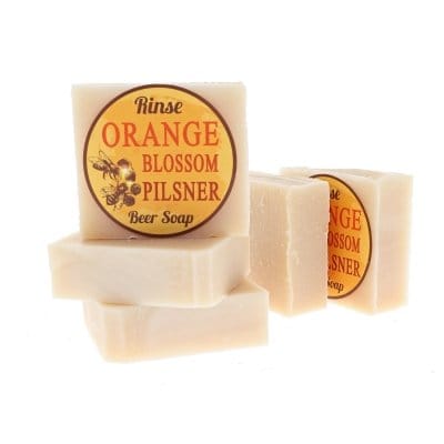 Orange Blossom Pilsner soap stands before stacked twins — bee art label on stark white