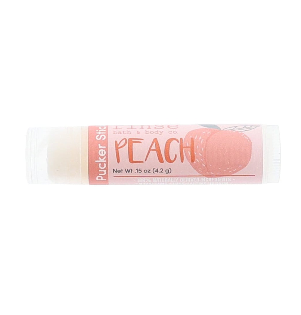Peach Pucker Stick lying on bright white — peach-toned label with fruit illustration in clean studio light