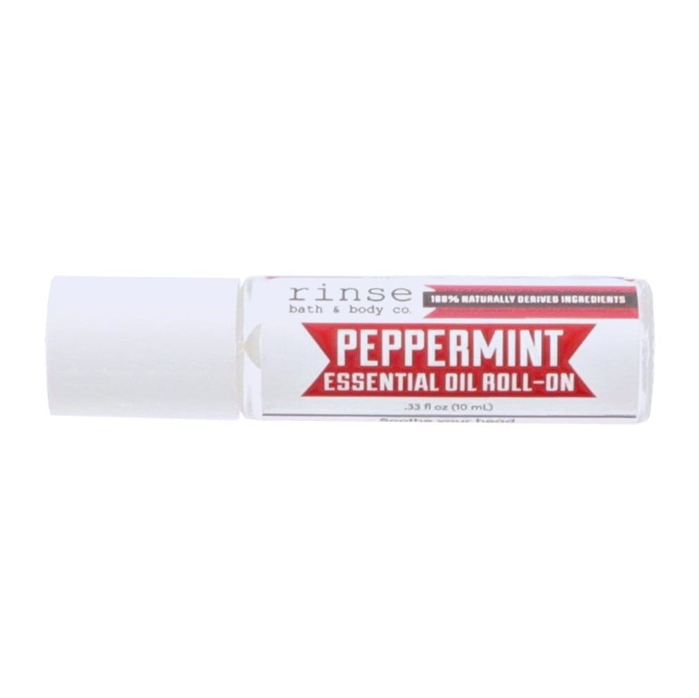 Peppermint roll-on lying on bright white — bold red banner label and white travel bottle in clean studio light