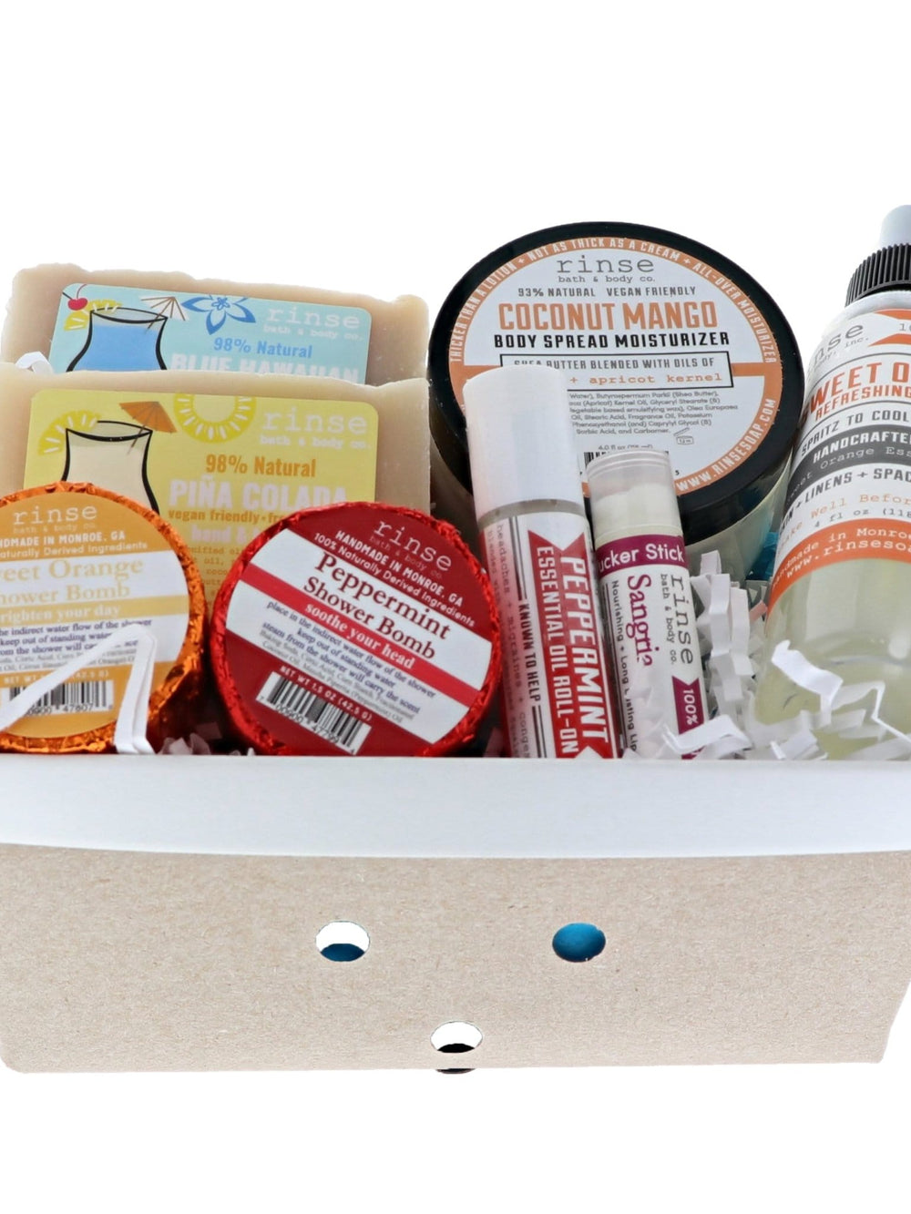 Staycation basket holds soaps spray and lip balms — colorful tins in a kraft window box on stark white