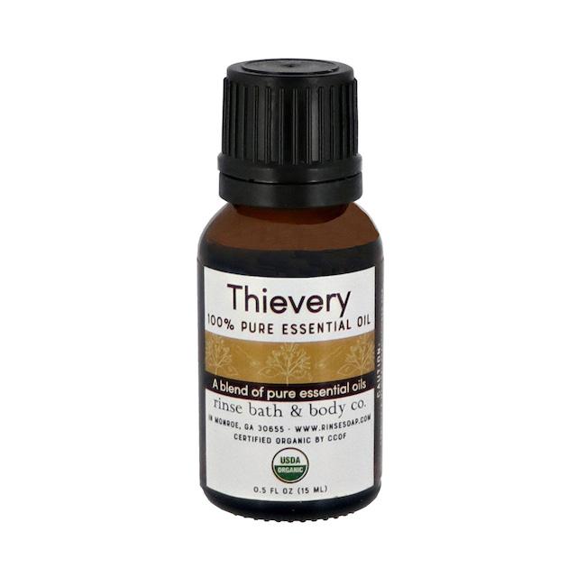 Amber Thievery essential oil bottle standing on bright white — black ribbed cap and gold band with USDA seal