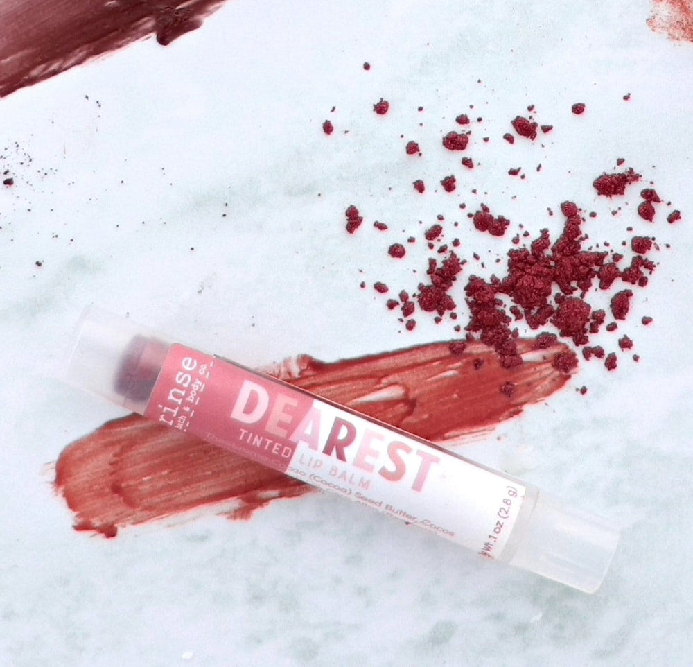 Dearest lip balm rests over a rich mauve smear — crushed berry pigment on soft marble
