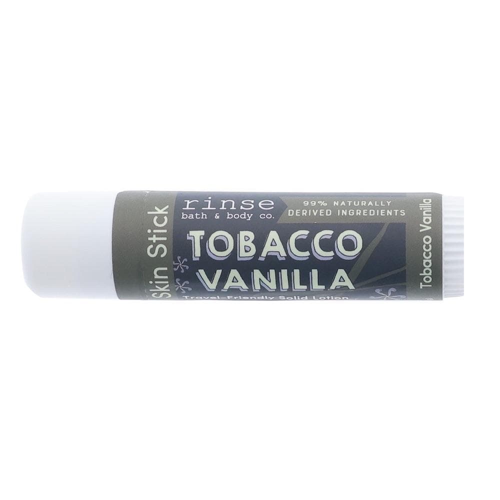 Tobacco Vanilla Skin Stick lying on bright white — charcoal label with teal accents in clean studio light