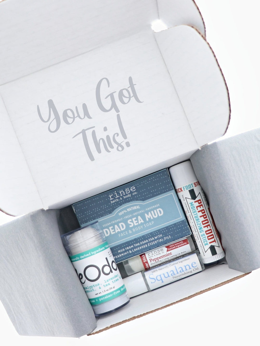 Open Trying Natural discovery box shows Dead Sea Mud soap, DeOdor, Peppofoot, and more on grey tissue — You Got This lid.