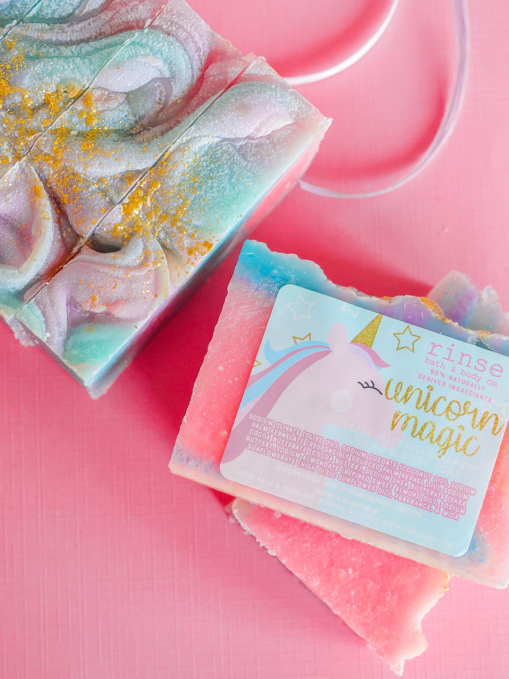 Labeled Unicorn Magic bar among glittered pastel soaps — pink ribbon edge on vibrant pink